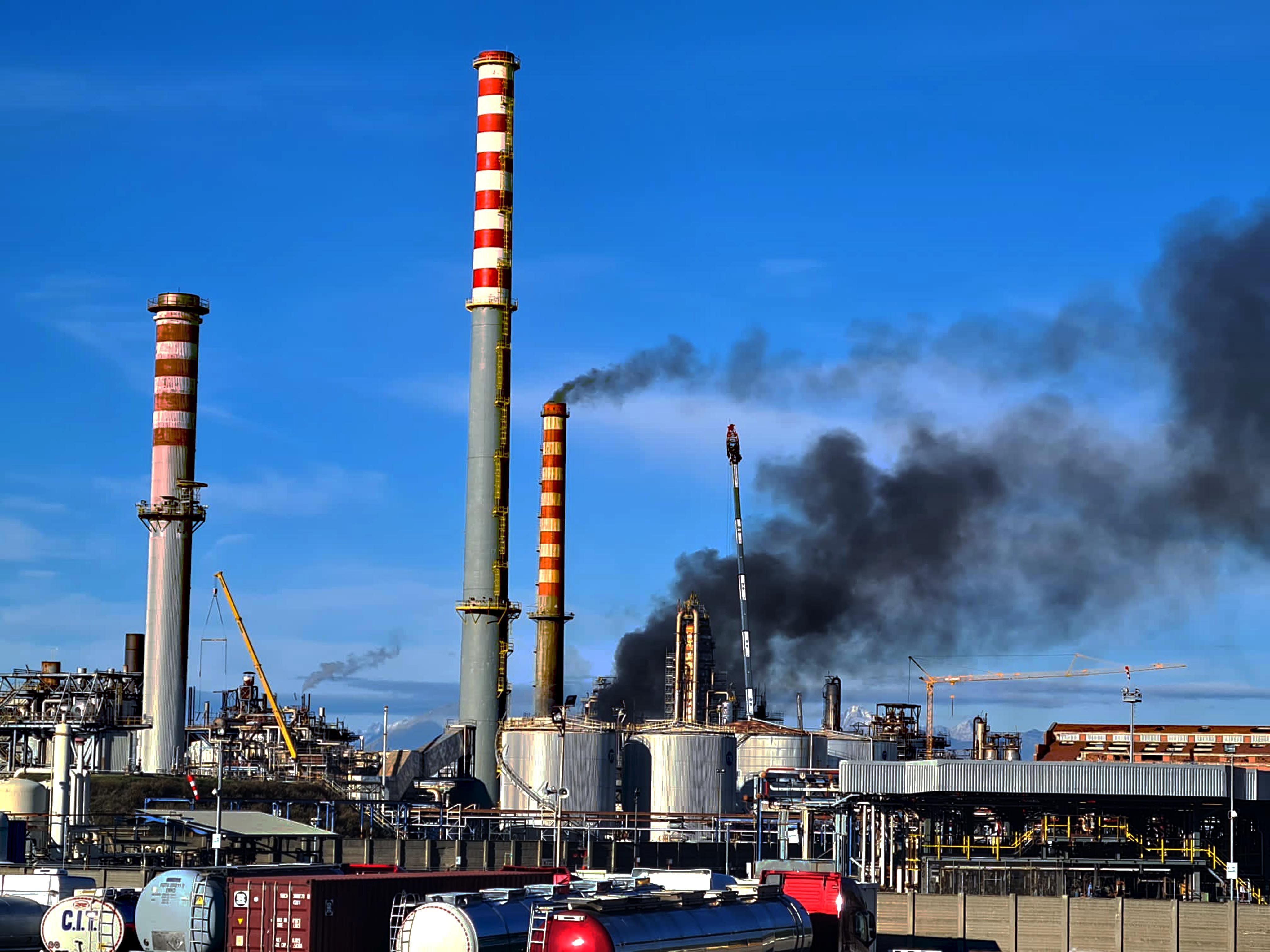 Le ciminiere della raffineria Eni a Stagno e, sullo sfondo, la nube di fumo nero che martedì pomeriggio si alzava dall’impianto danneggiato dal rogo (Franco Silvi)