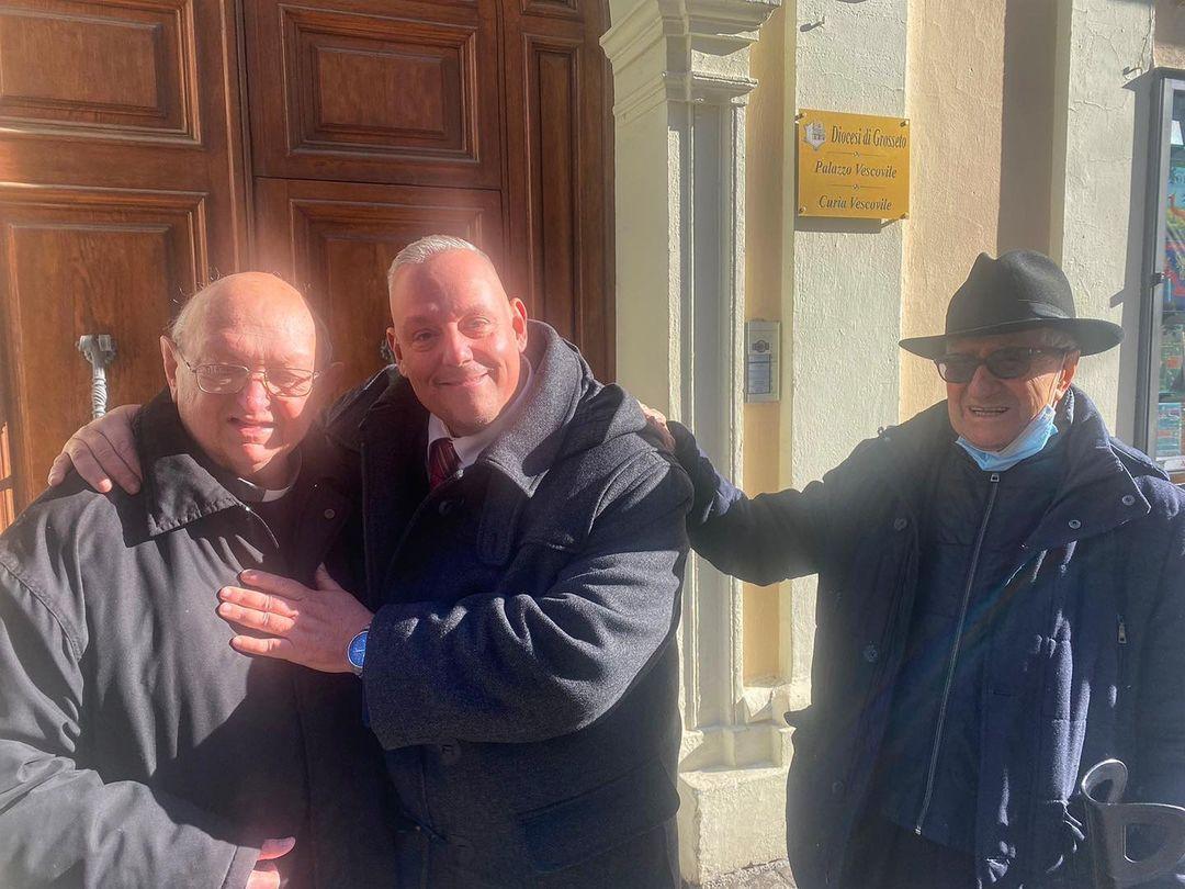 L'abbraccio tra don Piero e il sindaco Antonfrancesco Vivarelli Colonna sul sagrato del duomo, insieme a don Franco (a destra), nella foto postata da Vivarelli Colonna sul suo profilo Facebook