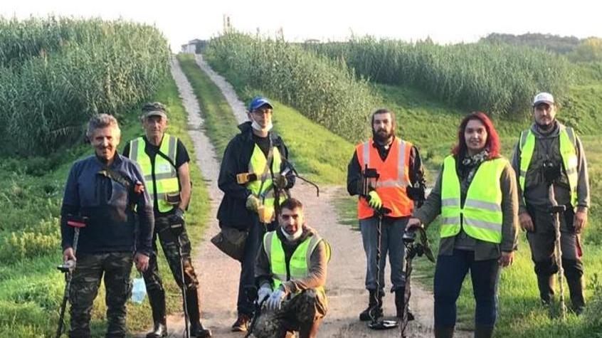 Volontari e metal detector in spiaggia o nel bosco a caccia di oggetti smarriti