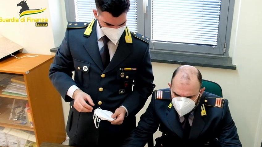 Due finanzieri esaminano una delle mascherine non in regola