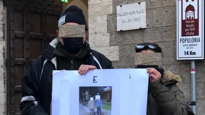 La coppia di genitori col cartello di protesta davanti al Comune