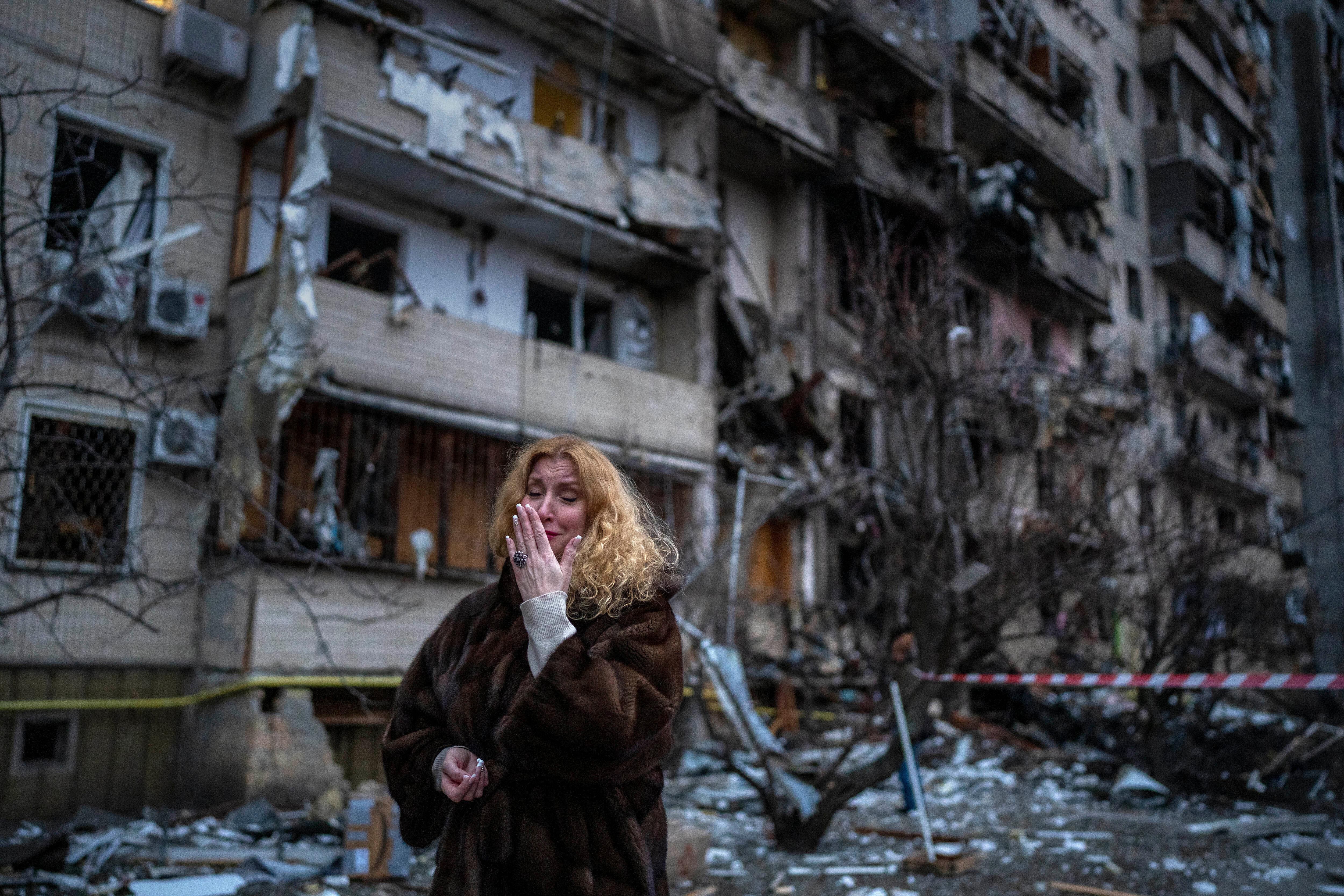 Una donna davanti a un palazzo danneggiato dai bombardamenti a Kiev