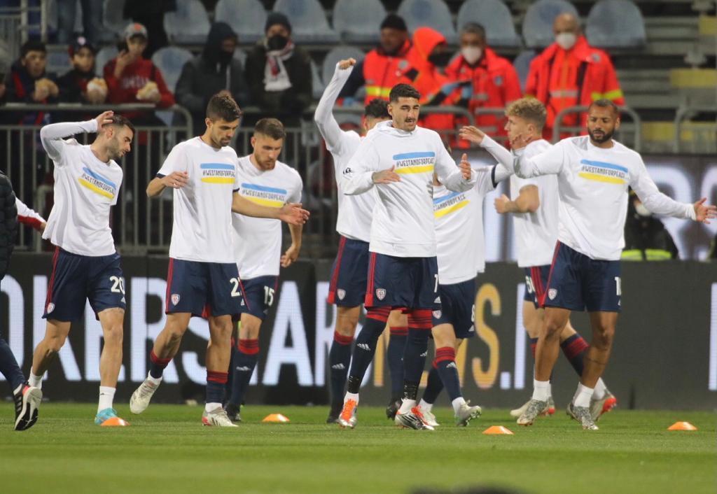Cagliari, giocatori rossoblù in campo nel pre-partita con i colori dell'Ucraina