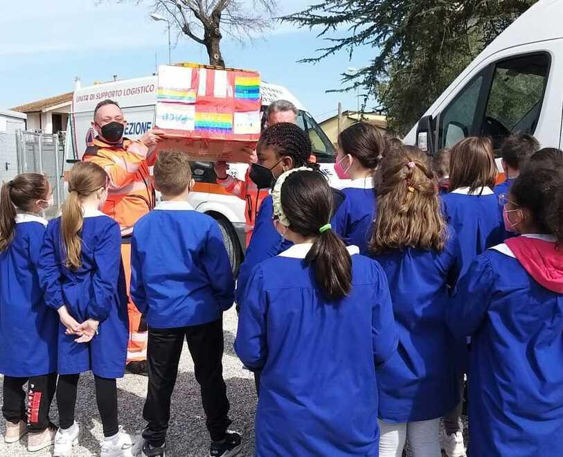 I volontari ricevono dai bambini lo scatolone coi soldi della colletta organizzata dai piccoli alunni