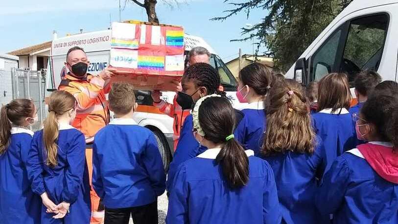 I volontari ricevono dai bambini lo scatolone coi soldi della colletta organizzata dai piccoli alunni