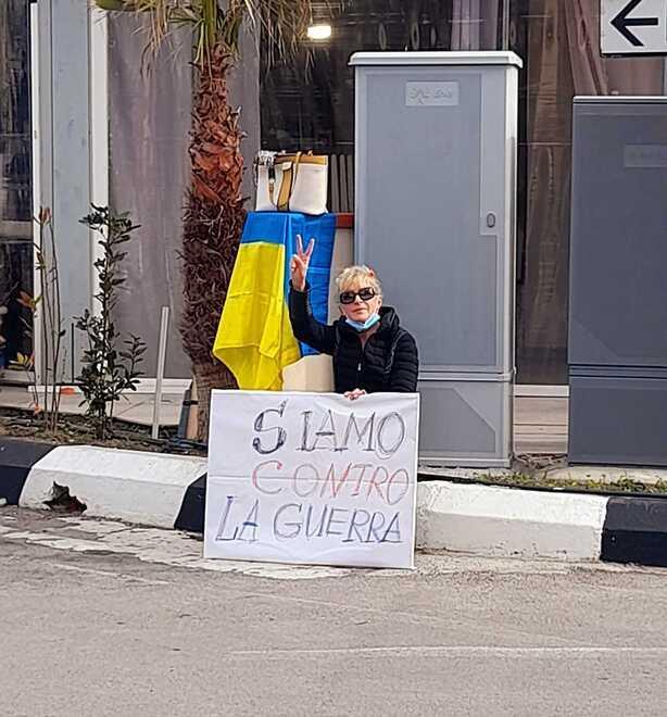 Una donna sul porto con un cartello contro la guerra