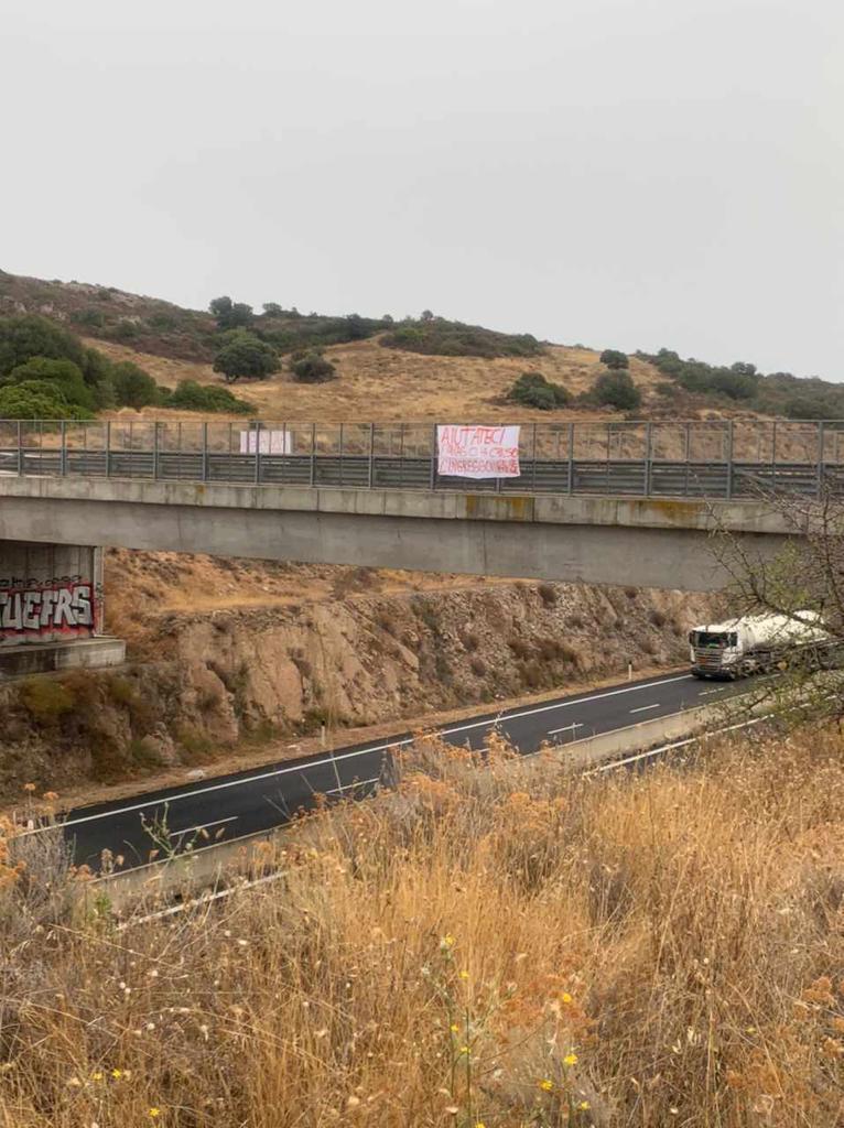 Cartellone di protesta lungo la strada dopo la chiusura col guard rail