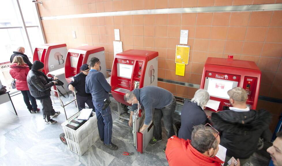Utenti in coda per pagare il ticket alle macchinette dell’ospedale, mentre i tecnici lavorano per riparare i guasti