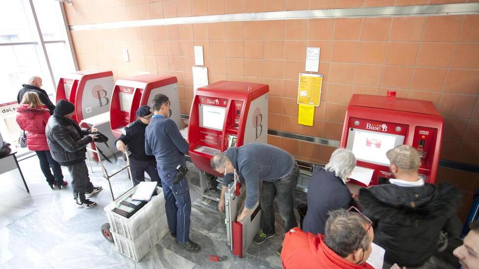 Utenti in coda per pagare il ticket alle macchinette dell’ospedale, mentre i tecnici lavorano per riparare i guasti