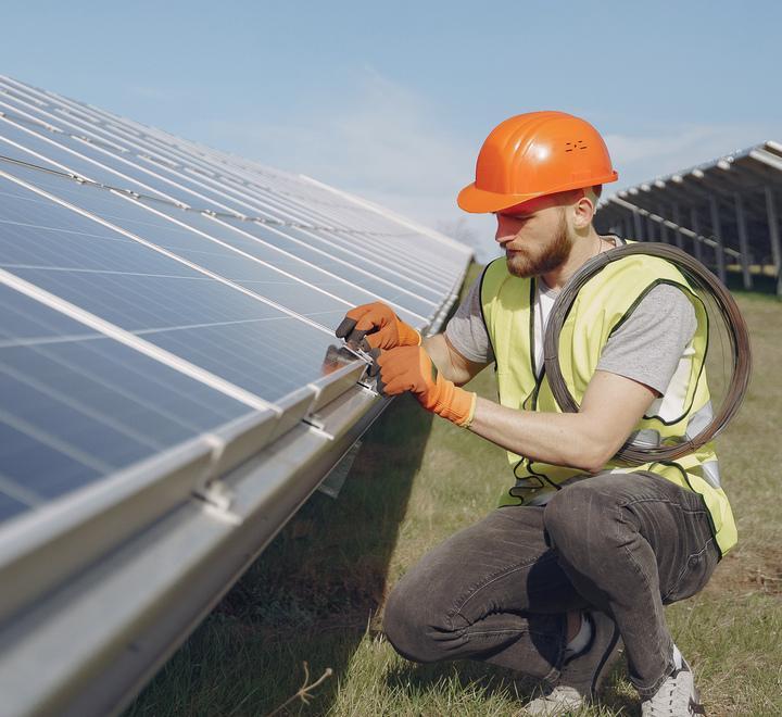 Un giovane operaio monta pannelli fotovoltaici (archivio)