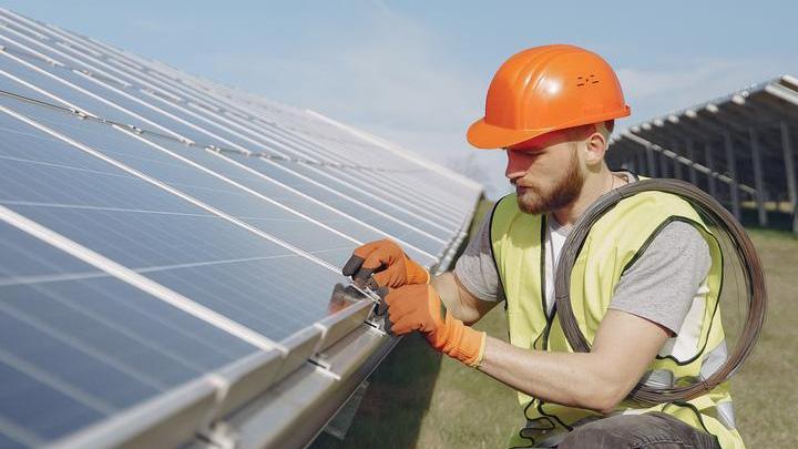 Un giovane operaio monta pannelli fotovoltaici (archivio)