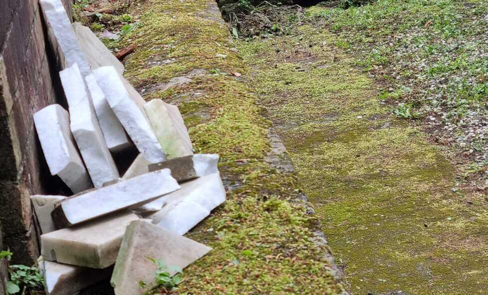 I pezzi della lapide caduti a terra e frantumati