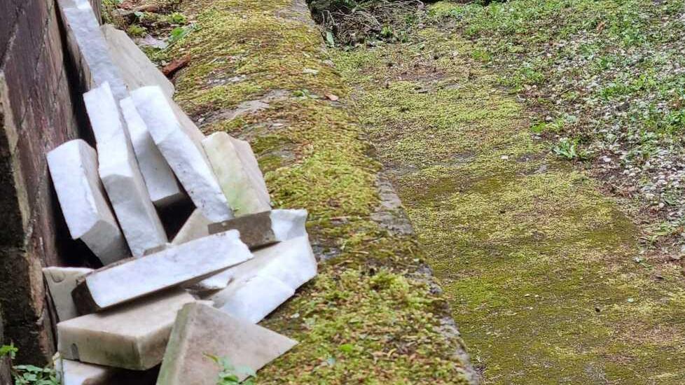 I pezzi della lapide caduti a terra e frantumati