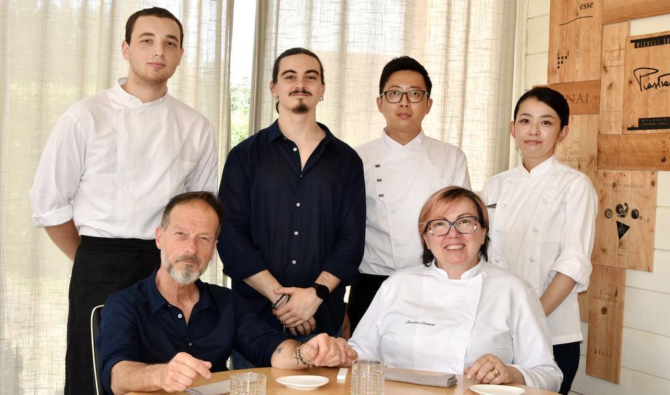 Barbara Simoncini seduta nella foto in alto insieme allo staff della locanda “Lo Scopiccio” di Perignano; accanto a lei il marito Fabrizio