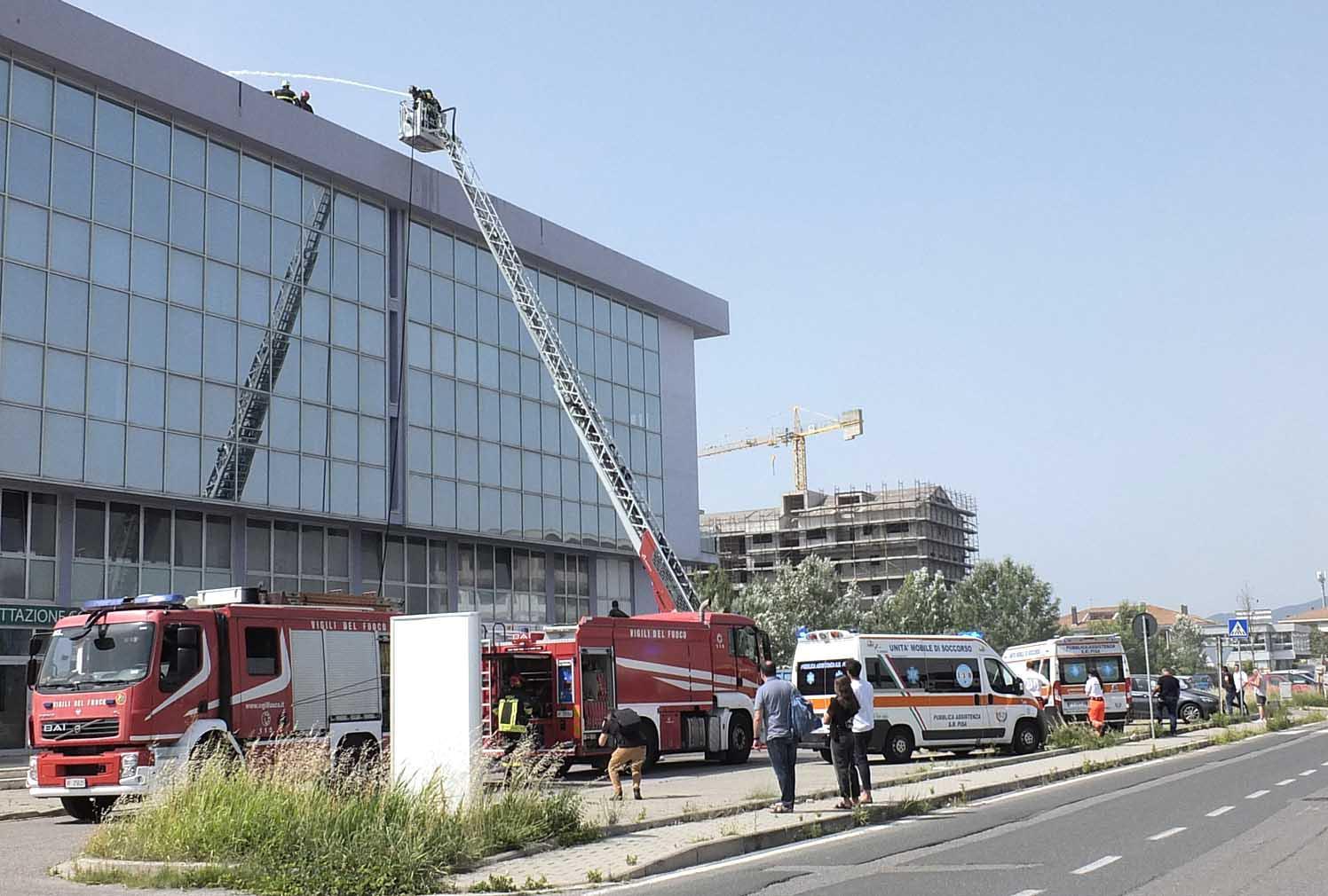 Il lavoro dei vigili del fuoco sul tetto del palazzo andato a fuoco nella zona industriale di Ospedaletto (Foto Fabio Muzzi)