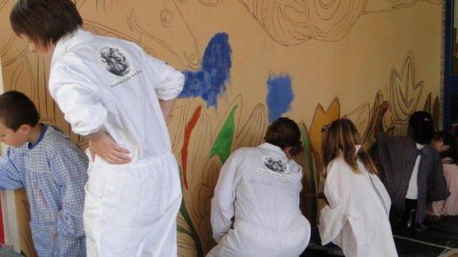 Studenti e bambini a dipingere insieme la scuola Arcobaleno