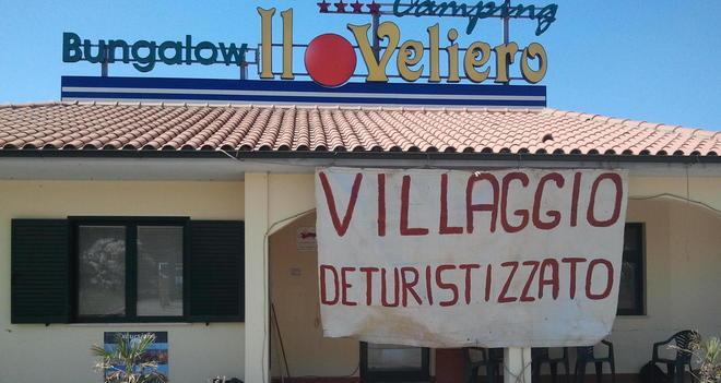 Uno striscione al villaggio per riaprire 