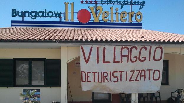 Uno striscione al villaggio per riaprire