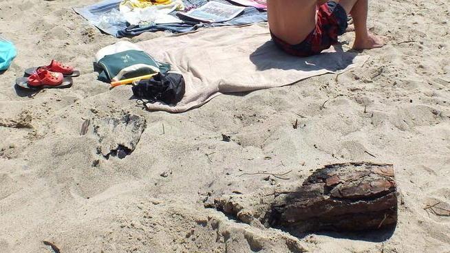 Vetri e resti di falò sulla spiaggia libera, puliscono i bagnanti