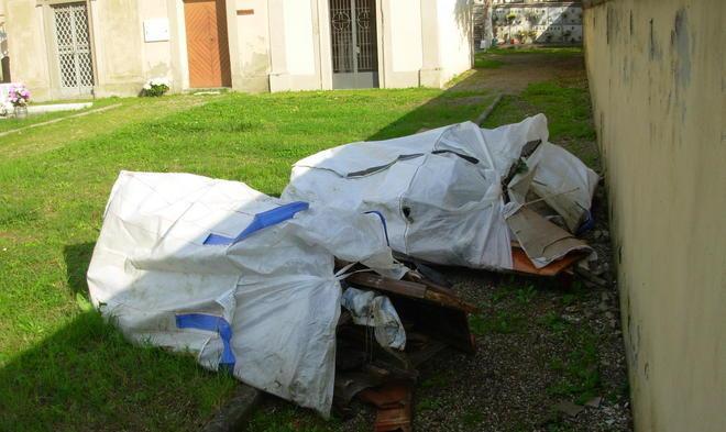Sacchi con resti di bare al cimitero 