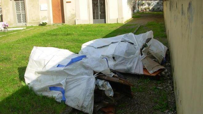 Sacchi con resti di bare al cimitero