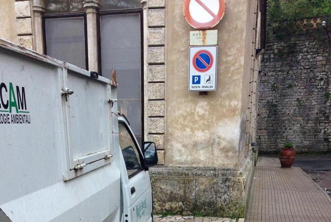 Furgone che raccoglie rifiuti posteggiato nel posto invalidi