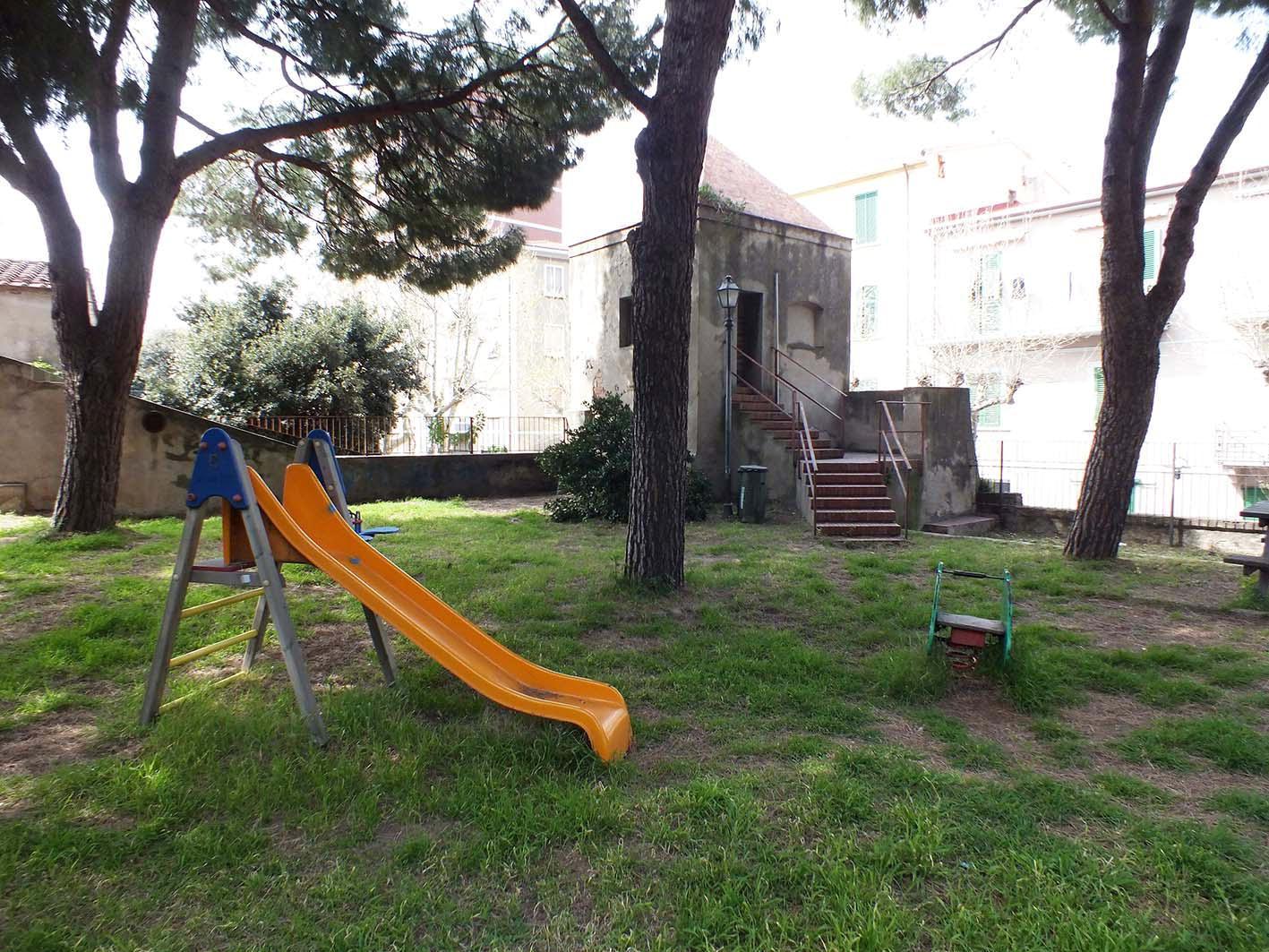 Centro come periferia, aree verdi con erba alta e giochi rotti 