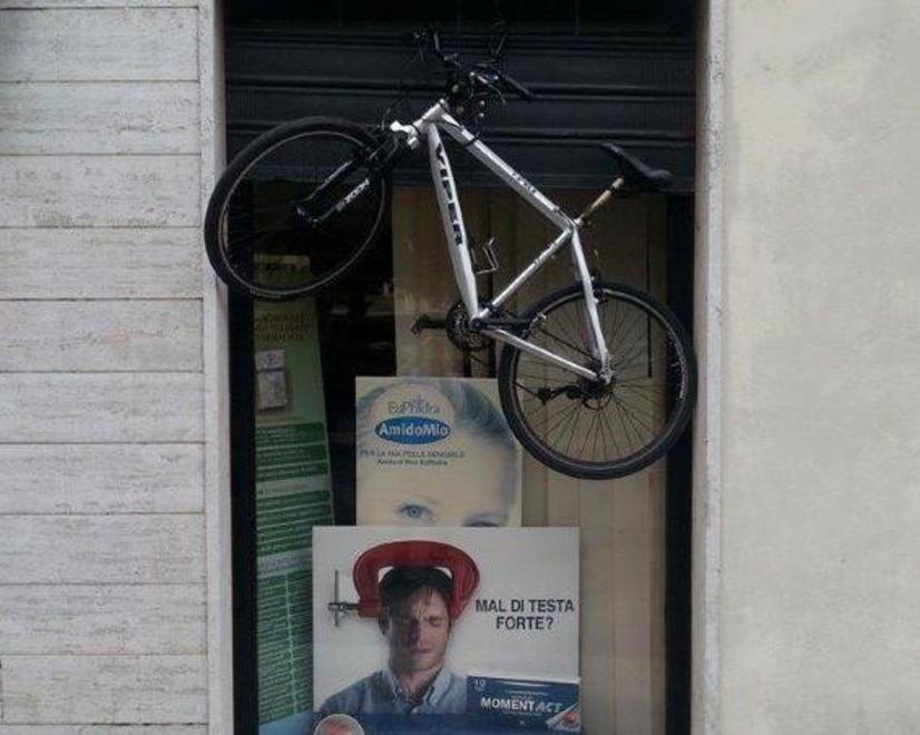 Nella piccola Atene la bici viene appesa a una farmacia 