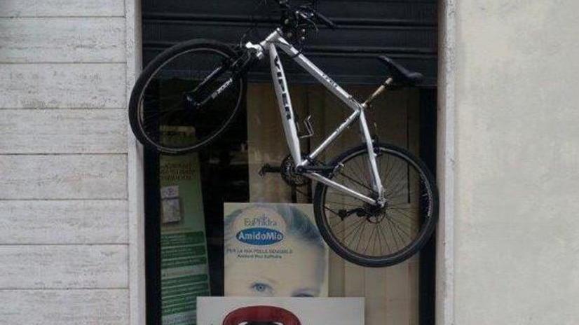 Nella piccola Atene la bici viene appesa a una farmacia