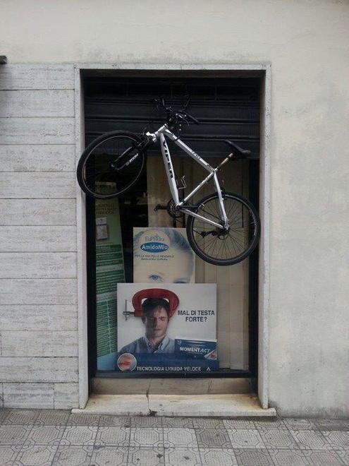 Nella Piccola Atene la bici viene appesa alla farmacia 