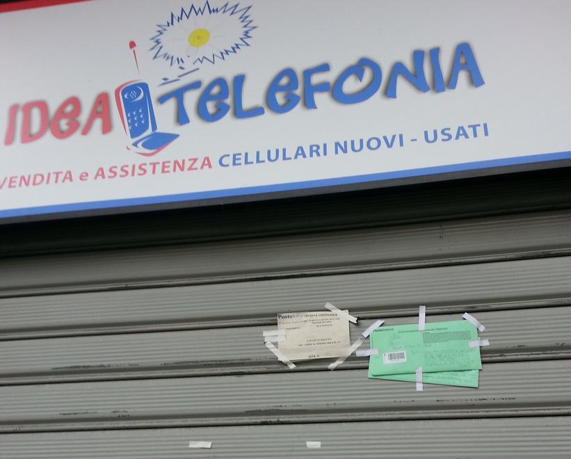 Avvisi di giacenza di posta affissi alla saracinesca 