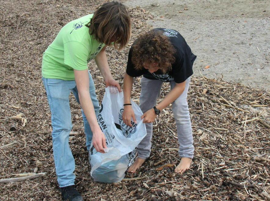 Bambini in spiaggia con guanti e sacchi 